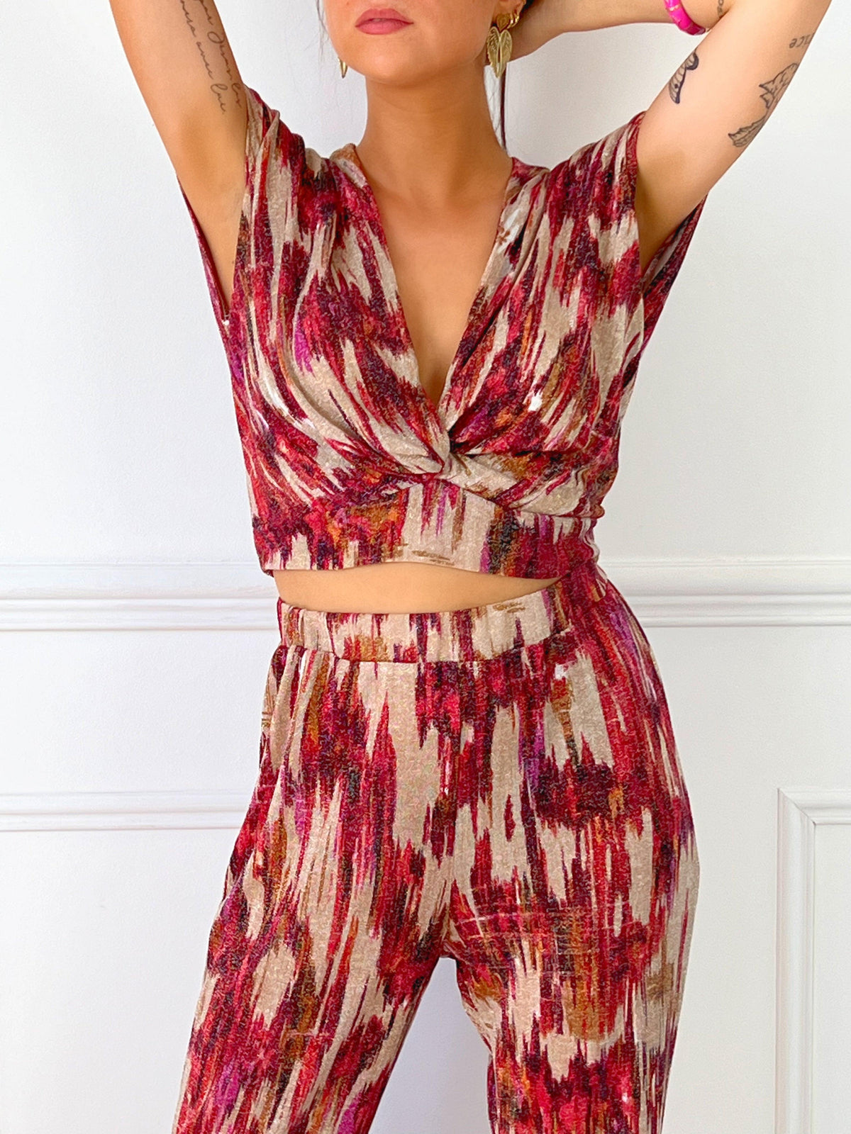 TOP FEMME SANS MANCHES PAILLETE  Top sans manches Col V devant Effet croisé sur le devant Pailleté sur tout le top Couleur : beige avec motifs rose, bordeaux, orange Matière légèrement extensible Elastique à l’arrière de la taille