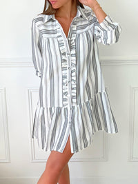 ROBE GRISE ET BLANCHE À VOLANTS Robe chemise Volants et boutons sur la longueur Col chemise Elastiquée aux poignets Coupe ample Motif rayure écrue et grise Couleurs : blanc et gris Composition : 60% Coton 30% Viscose Lavage à la main