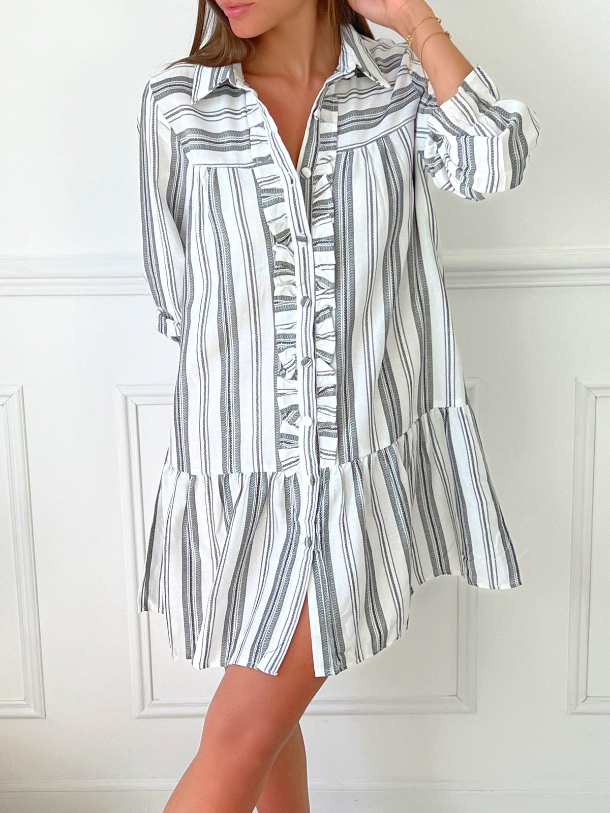 ROBE GRISE ET BLANCHE À VOLANTS Robe chemise Volants et boutons sur la longueur Col chemise Elastiquée aux poignets Coupe ample Motif rayure écrue et grise Couleurs : blanc et gris Composition : 60% Coton 30% Viscose Lavage à la main