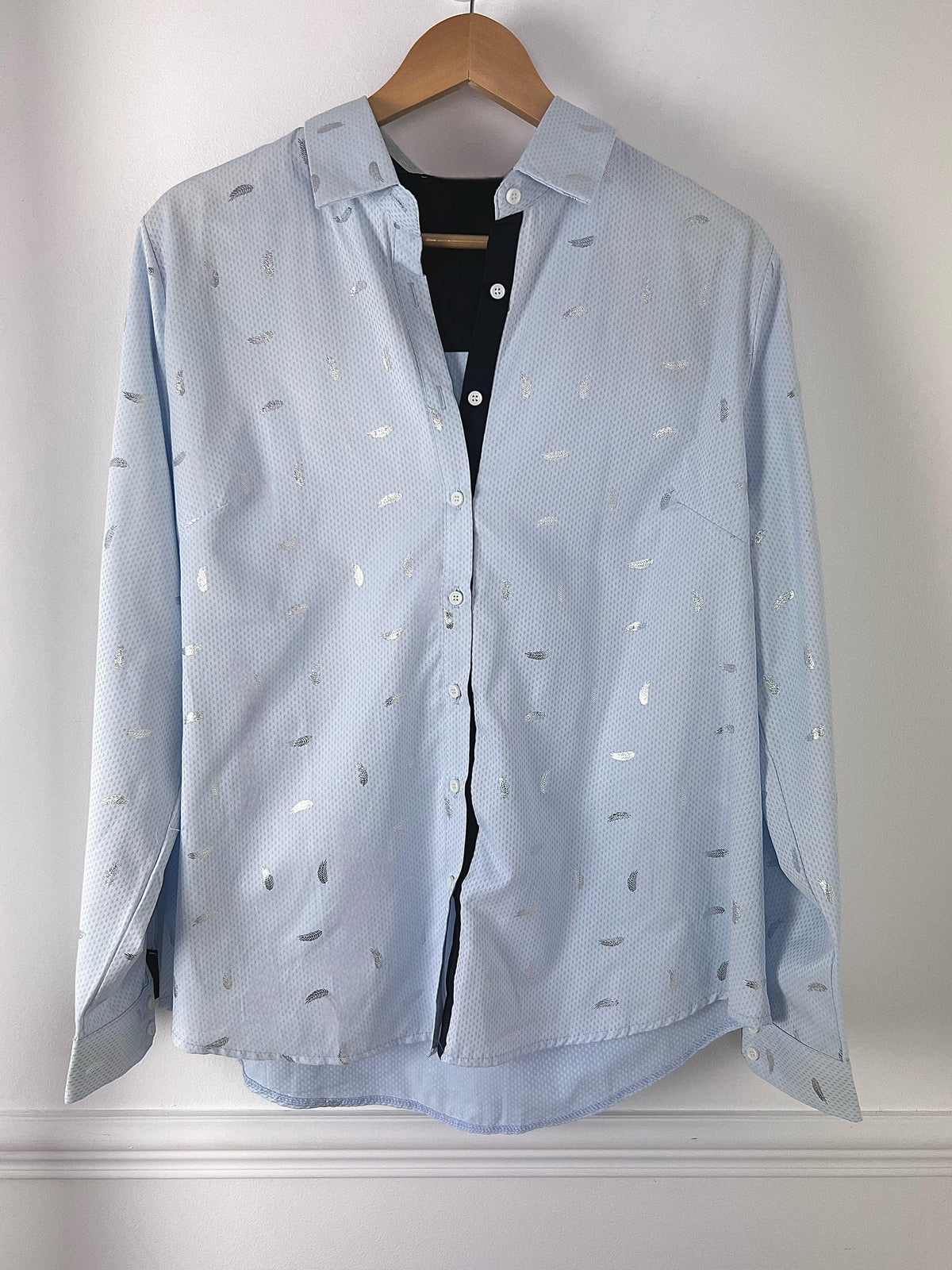 CHEMISE BLEUE A DETAILS ARGENTES CURVE FEMME Chemise manches longues Motifs plumes argentées Col chemise Boutons écrus sur la longueur et aux poignets Couleurs : bleu clair et bleu marine sur la longueur des boutons, aux poignets et haut du dos interne Composition : 55% polyester 45% Coton Lavage à la main obligatoire Made in P.R.C