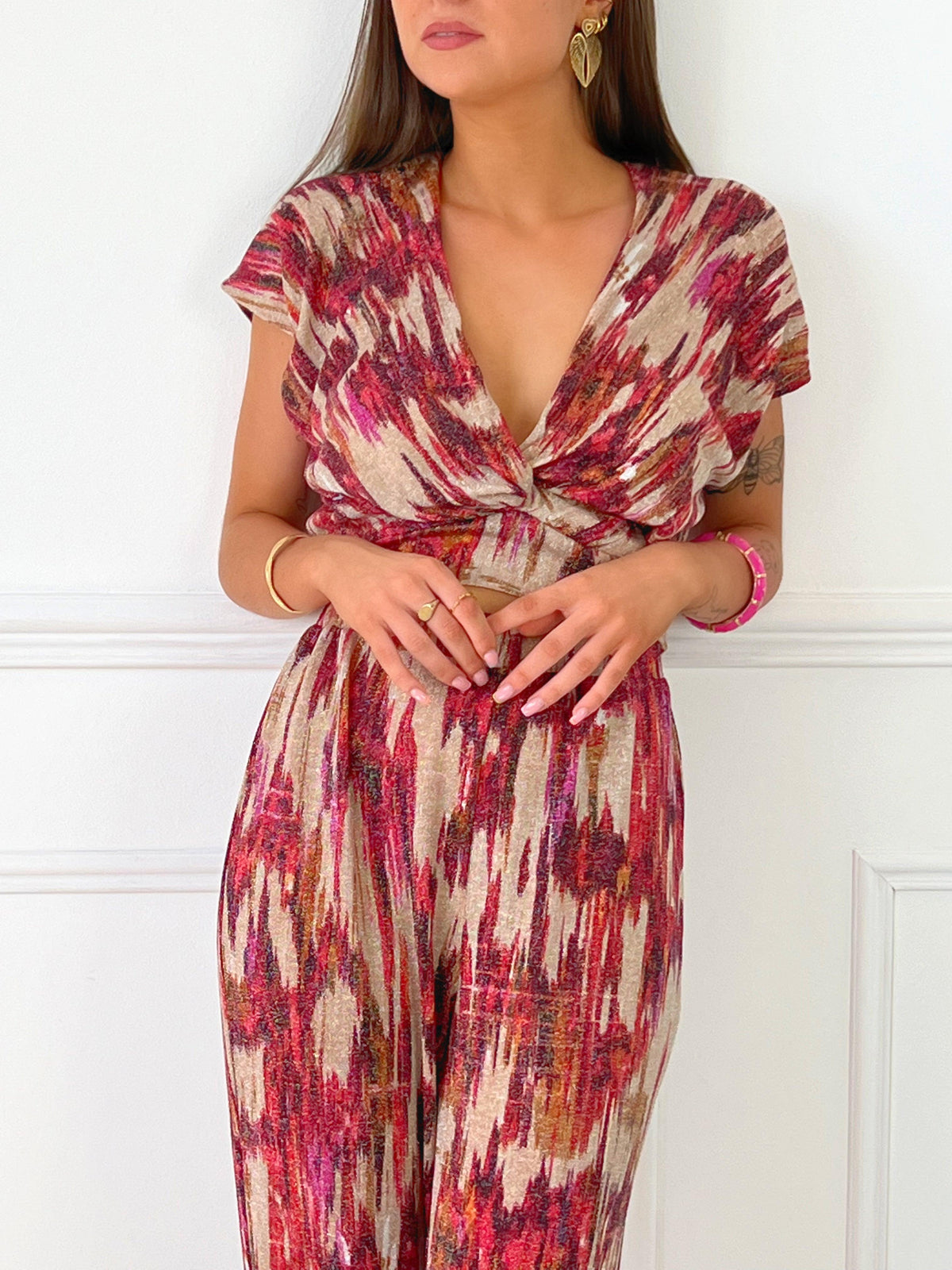 TOP FEMME SANS MANCHES PAILLETE  Top sans manches Col V devant Effet croisé sur le devant Pailleté sur tout le top Couleur : beige avec motifs rose, bordeaux, orange Matière légèrement extensible Elastique à l’arrière de la taille